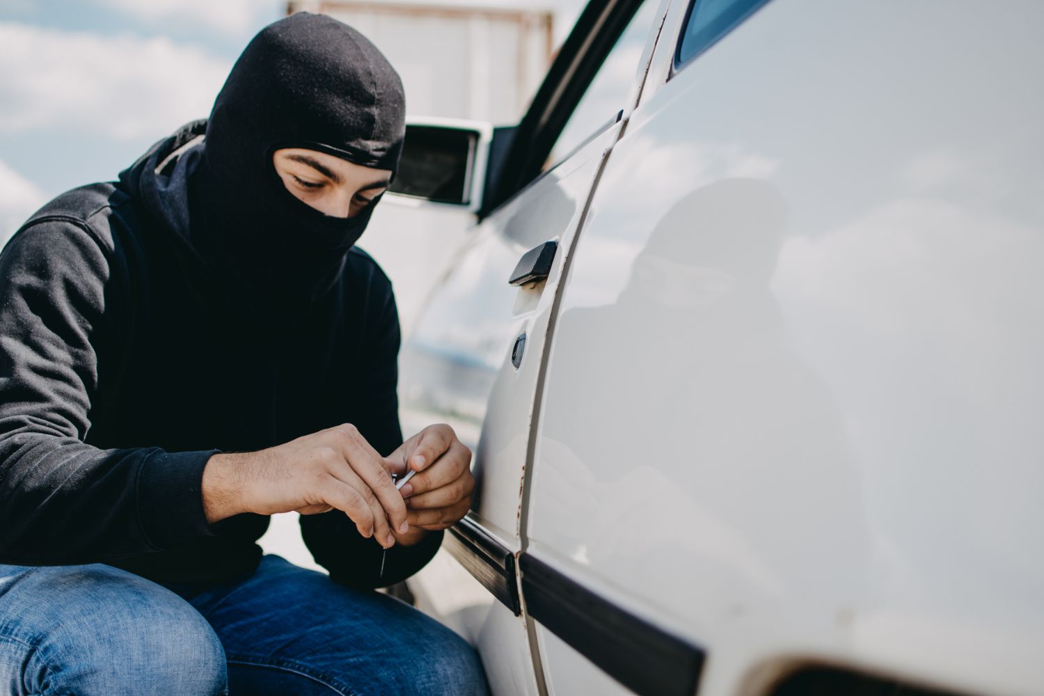 Thief trying to lock pick a car to steal it