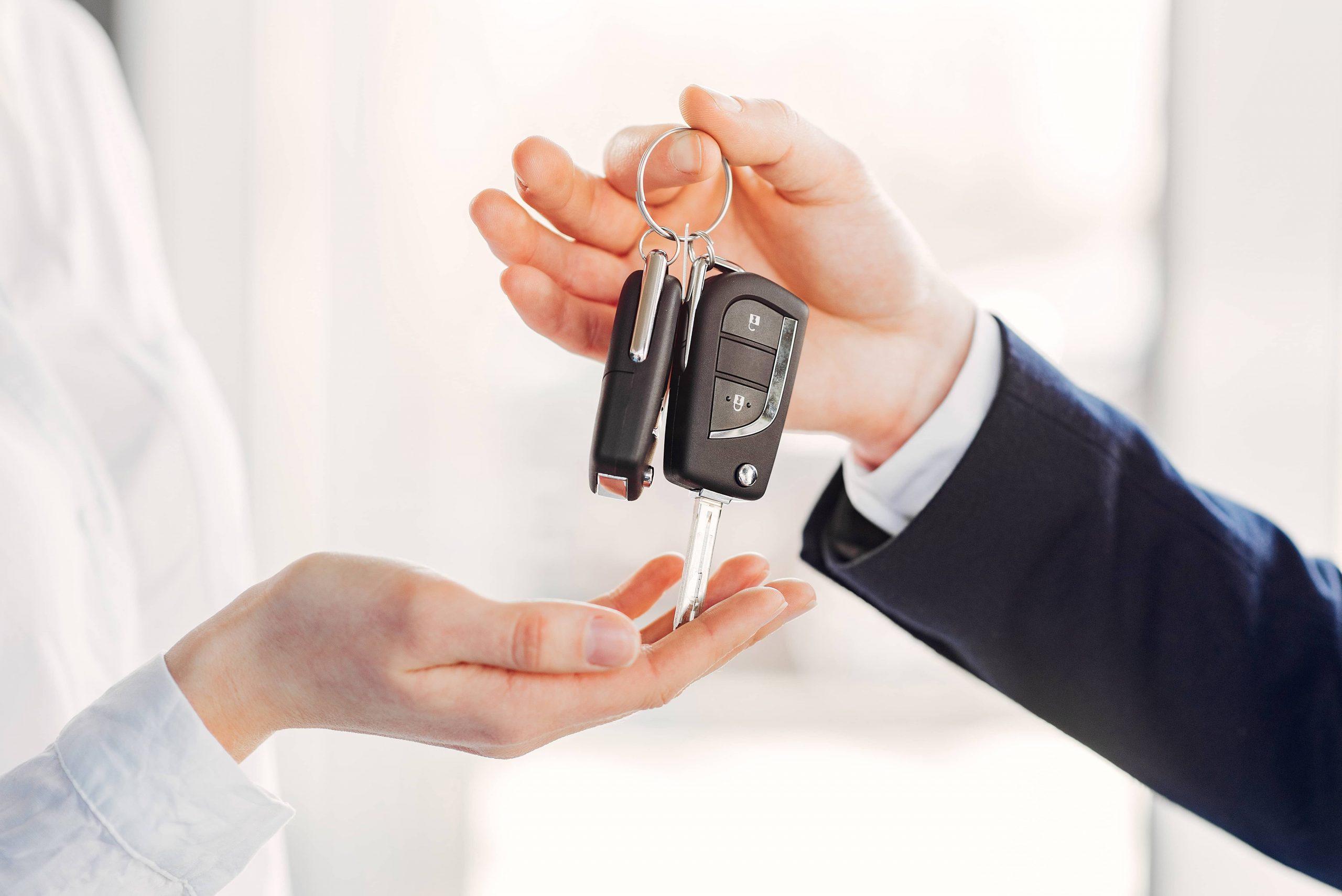 Car salesman handing keys to buyer for new car