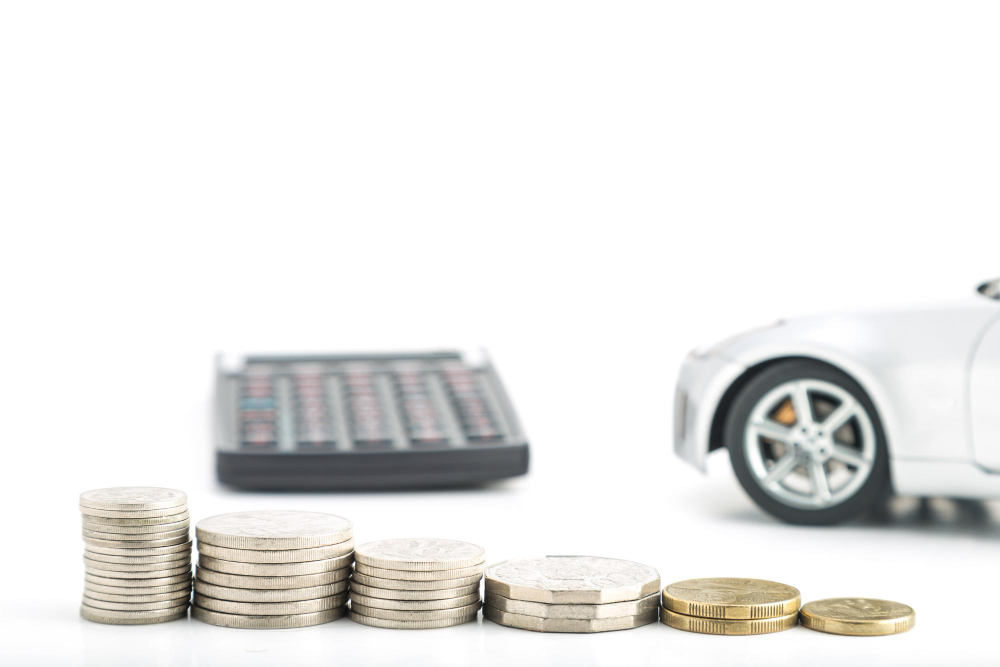 A calculator, row of coins, and the front of a toy car.